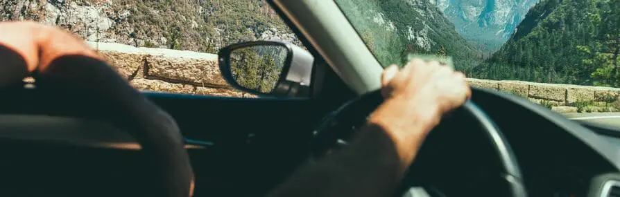 Um motorista circula por uma estrada pensando nas vantagens do seguro de carro.