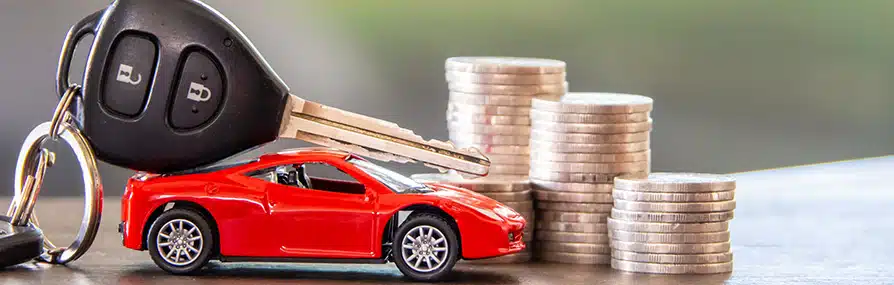Carro de brinquedo e chaves perto de moedas simbolizam custos de seguro de automóvel.